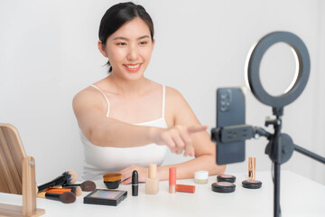 Asian blogger doing makeup and skin care tutorials live on her mobile phone over the internet.