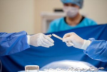Team of surgery doctor in Operating Room hold hands scalpel surgical blade give to Surgeons During...