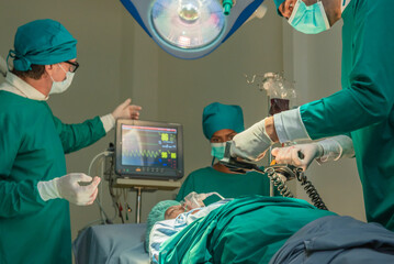 Team of surgery doctor using defibrillator pump chest heart patient to save life while medical...