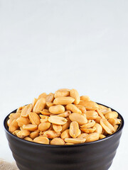 Cup filled with peeled peanuts on light background with copy space. Card for marketplaces.