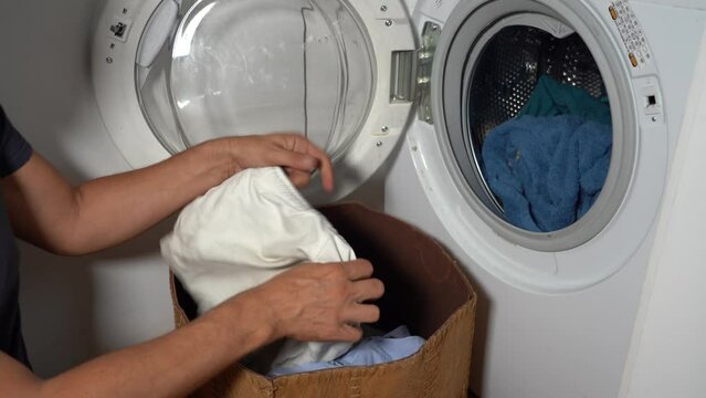 40 years old single man do the washing machine to wash dirty clothes - separate the whites from the colored before starting the automatic washing in the laundryA FARE 1
