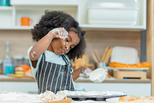 african afro black daughter kids sifting flour powder and sprinkling ingredients on massaging dough for bakery cooking. Black african daughter afro hair enjoy sifting flour wheat by sieve in kitchen
