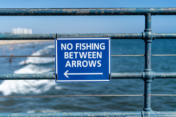 No fishing between arrows sign on the pier