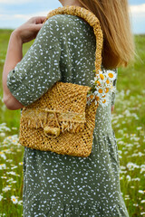A young woman in a dress is holding a straw bag with a bouquet of daisies. Happy lady and nature - the concept of harmony. The idea of self-care, healthy lifestyle and positive