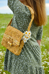 A young woman in a dress is holding a straw bag with a bouquet of daisies. Happy lady and nature - the concept of harmony. The idea of self-care, healthy lifestyle and positive