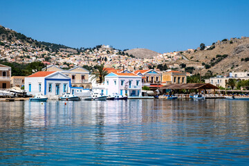 Fototapeta premium Colorful Houses by the Mediterranean Sea on Pedi Harbor, Symi, Greece