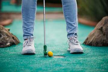 Golfer playing adventure or mini golf and trying putting ball into hole. Summer sport activity