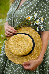 A young woman in a straw hat  on a chamomile field. Happy lady and nature - the concept of harmony. The idea of self-care, healthy lifestyle and positive