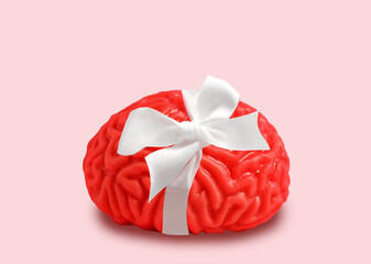 Bright pink human brain model with satin bow on pastel background. Creativity, inspiration and mental health concept.