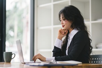 A portrait of a smiling, young, beautiful, professional, and confident millennial caucasian businesswoman using a digital tablet to analyze sales data at a modern office.