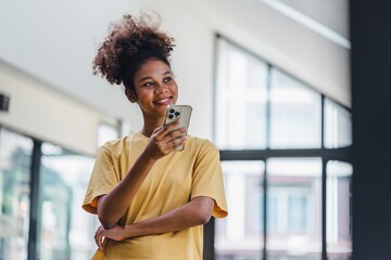Portrait of happy young African american woman smiling confident using smartphone. afro american...