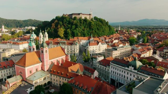 Establishing Aerial view of Ljubljana Castle on hill in historical city. Capital of Slovenia, Central Europe. Ancient chateau with Slovenian flags and buildings of old town. 4k drone zoom in shot