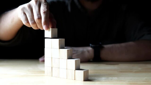 hand stacking wood block as step stair, business development, business growth success on dark background. Concept of Business growth, Financial planning, Investment, Strategy