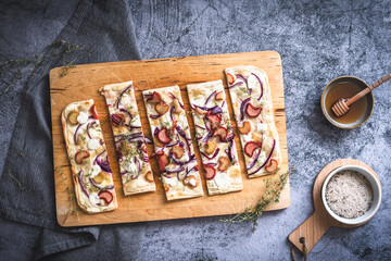 Baked tarte flambee with rhubarb, red onions, goat cheese and honey, cut into strips - obrazy, fototapety, plakaty