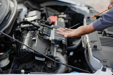 Fototapeta na wymiar A mechanic checks the engine oil level. off-site car service.