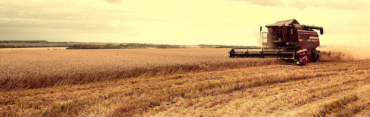 Combine Harvester Working in a Field on a Farm. Seasonal Harvesting the Wheat. Agriculture. Panoramic Banner. Vintage style.