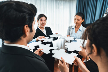 Multiethnic business people holding jigsaw pieces and merge them together as effective solution...