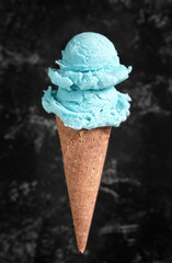Blue ice cream in a waffle cone on a dark background