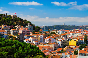 Lisbon famous view from Miradouro dos Barros tourist viewpoint over Alfama old city district with St. George's Castle and Portugal flag, 25th of April Bridge, Christ the King statue. Lisbon, Portugal.
