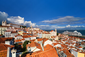 Fototapeta na wymiar View of Lisbon famous postcard view from Miradouro de Santa Luzia tourist viewpoint over Alfama old city district, moored cruise liner and moving clouds. Lisbon, Portugal