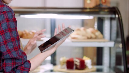 Close-up hands bakery worker, laptop in hand, check cakes, desserts, bakery products stored in refrigerator, which order should add how many pieces have been sold, Increase sales for own branch.