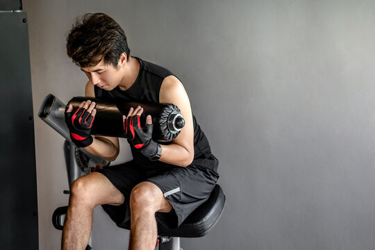 Active Asian sport man with well trained body in black sportswear doing workout with abdominal crunch machine or seated ab crunch in fitness gym. Physical training exercise to get six packs