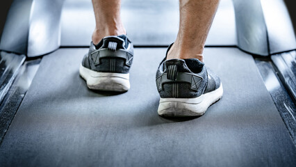 Close up of male feet in sneakers or sport footwear running on treadmill in fitness gym. Indoor...