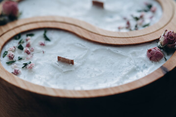 Handmade aroma concept. Soy candle in wooden yin and yang shape and dry flowers scented with natural wax close-up