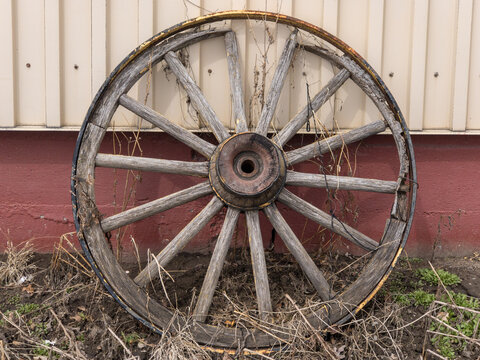 old wagon wheel leaning against a barn