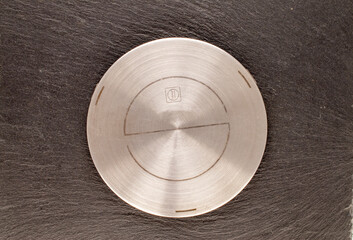 One metal adapter  for induction surface on slate stone, macro, top view.