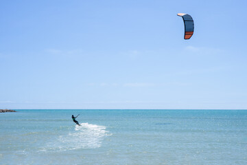 Rear view of a kitesurfer riding his kite in a calm sea