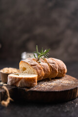 Sliced artisan baguette bread on wooden coaster and rustic background. Sourdough bread.