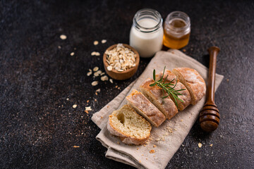 Sliced artisan baguette bread on wooden coaster and rustic background. Sourdough bread.