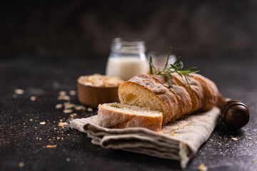 Sliced artisan baguette bread on wooden coaster and rustic background. Sourdough bread.