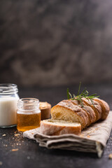 Sliced artisan baguette bread on wooden coaster and rustic background. Sourdough bread.