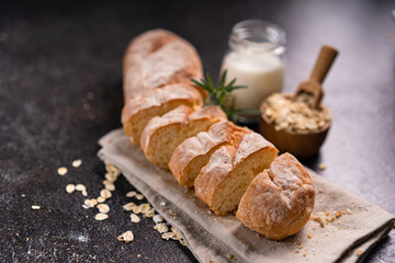 Sliced artisan baguette bread on wooden coaster and rustic background. Sourdough bread.
