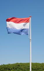 Flag of the Netherlands waving in the wind against a clear blue sky