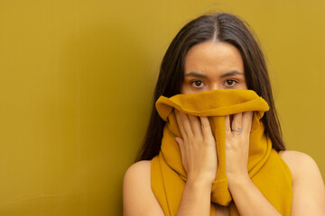 Ethnic woman covers her face with a scarf. Background combining with skin and clothes. Fashionable.