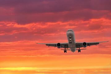Fototapeta na wymiar Airplane landing against golden sunset