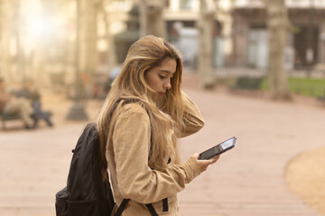 Young woman looking at smartphone in city square as a guide. Travel alone concept