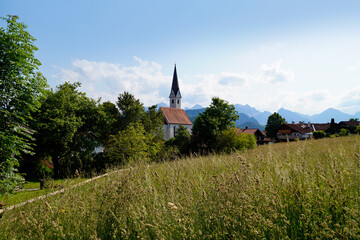 Fototapeta na wymiar a scenic alpine view with lush green alpine meadows and an old church in the alpine village Schwangau in the Bavarian Alps on a summer day (Allgaeu, Bavaria, Germany) 