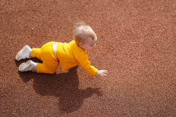 Top view of the baby toddler crawling across the playground on the floor