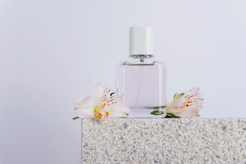 Obraz na płótnie Canvas Perfume bottle and white alstroemeria flowers on natural stone podium, closeup. Copy space