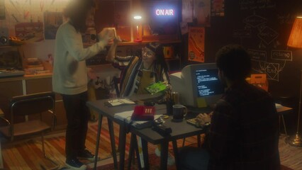 Wide shot of young man and woman finishing work on computer hardware detail then doing fist bump and high five with their co-worker, startup in 90s concept - Powered by Adobe