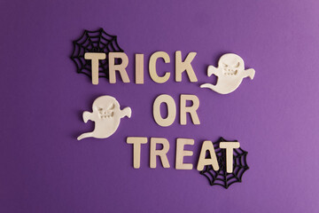 Trick or treat lettering on purple background with halloween decor cobweb and ghost