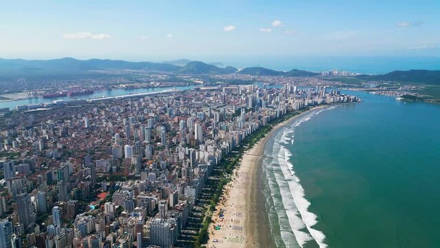 Ascending view of the coastal city in Brazil. Aerial view of the entire Baixada Santista. Beach with colorful umbrellas and beautiful waves. Port of Santos in the background. Santos, S&atilde;o Paulo, Brazil