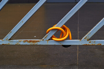 Yellow cable lock bicycle fastened to metal grill.