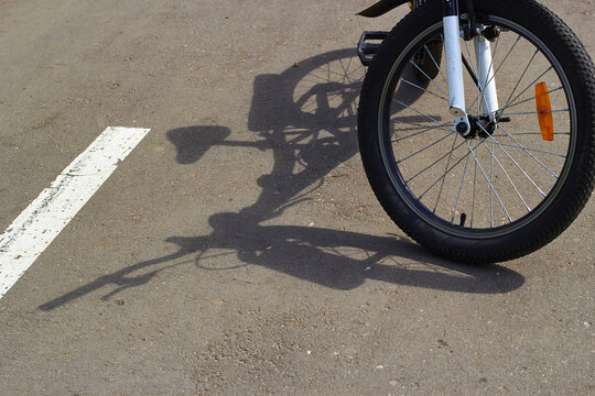 bicycle shadow on gray asphalt. Sunny day wheel