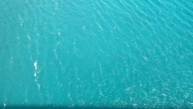Aerial view of aquamarine sea surface. Rough sea texture. Top view natural background of rippled sea-green sea water. Marine theme with copy space.