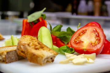 Vegetables for Spanish cold gazpacho soup cucumbers, peppers, tomatoes, bread are on the board